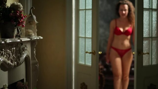 Woman in underwear gets up from the sofa and passes through door