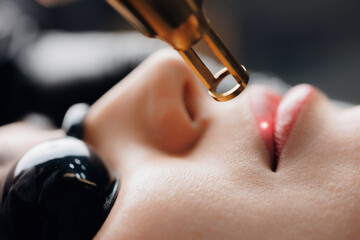 Laser removal of tattoo permanent makeup red color from lips of woman in salon