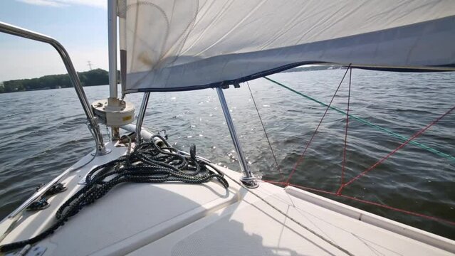 Empty bow of sailing yacht with ropes and sail on reservoir 