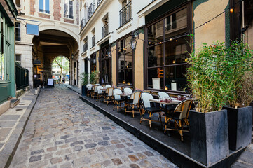 Fototapeta na wymiar Cozy street near Boulevard San-German with tables of cafe in Paris, France. Architecture and landmark of Paris. Paris cityscape