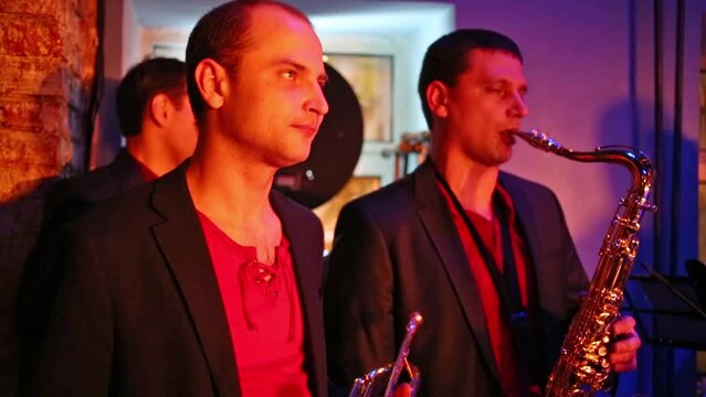 Three musicians of band are playing at musical bar.