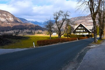 House next to a paved road in Stara Fužina village in Bohinj and Julian alps mountain in Slovenia