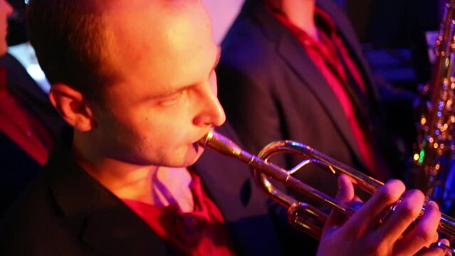 Men with a trumpet and sax of band are playing music at musical bar