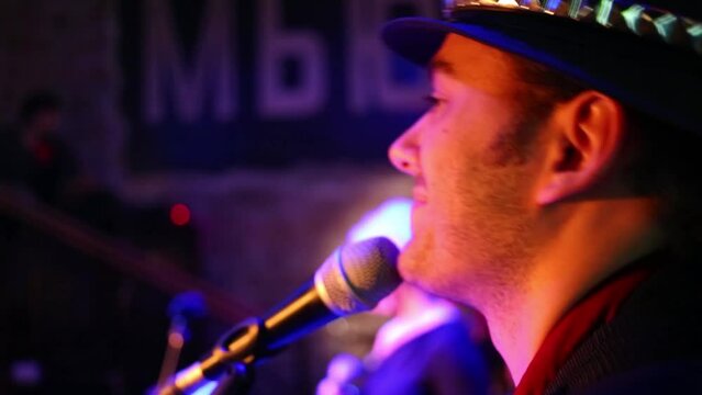 Musician in a hat of band is singing at the musical bar.