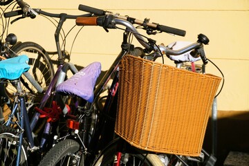 Fahrräder mit braunem Korb aus Bast vor beiger Hauswand in Stadt bei Sonne am Mittag im Winter