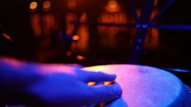 Man is playing one hand on the bongo, close up view.