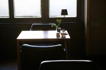 Innenausstattung von Café mit kleinem Holztisch und zwei braunen Stühlen aus Leder vor Fenster am...