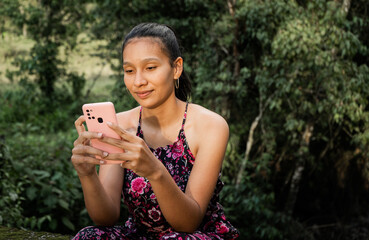 joven mujer sentada al aire libre escribiendo en su celular 