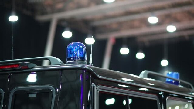 Blue flasher is standing on the top of black car at exhibition 