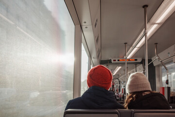 Interior inside tram and back view of couple passenger wear beanie sit next each other against...