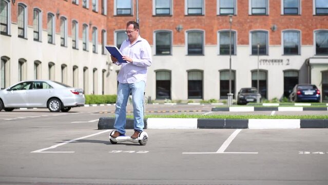 Man drive circle wise on self-balancing scooter and look in folder