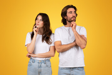 Pensive couple in white t-shirts and blue jeans, standing back-to-back with thoughtful expressions