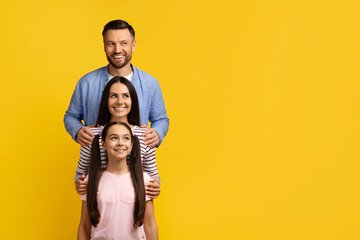Obraz premium Happy Young Family, Mother Father And Daughter Embracing While Standing In Line