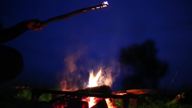 Hand burn stick in fireplace and ted sparks at night.