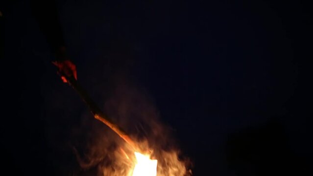 Hand with stick ted fireplace with many sparks at night.
