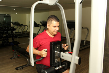 40-year-old dark-skinned Latino man does exercise to exercise his arm and chest as rehabilitation for surgery due to an accident