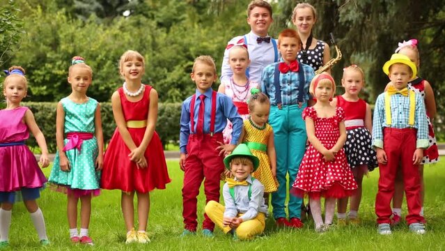 Fifteen children of different ages in bright clothes in summer park