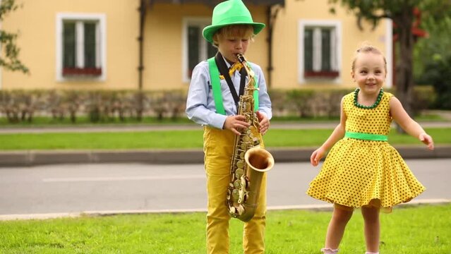 Boy and girl on the street, boy playing saxophone and girl dancing