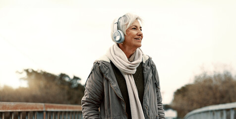 Senior woman, headphones and music outdoor, walking and wellness with audio streaming and energy....