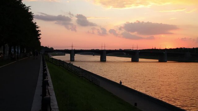 Embankment with unrecognizable people and sunset sky 