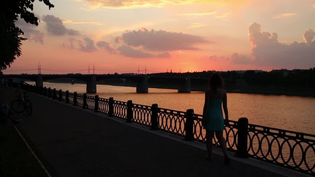 Back of woman coming to barrier on embankment of Volga river