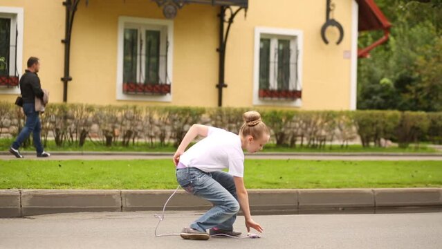 Girl in jeans and white t-shirt jumping rope outdoors