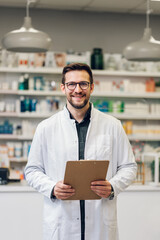 A pharmacy intern doing inventory in a drug store while smiling at the camera.