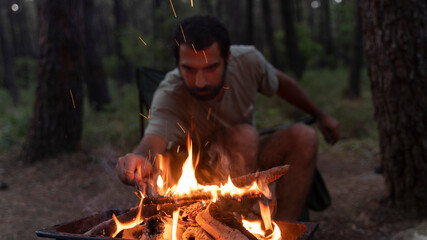 Summer vacation concept. Camping, hiking, lifestyle. Hipster hiker with mug relax at bonfire in forest. Travel, traveling, wanderlust. Man traveler drink tea at campfire flame.