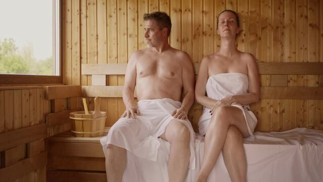 Couple relaxing in hot sauna. Authentic, real sauna moment.