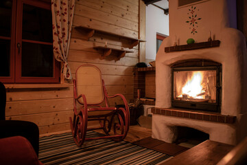 rocking chair in a wooden house by a burning fireplace