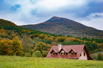 a picturesque, colorful view of the mountains in the autumn aura and a house in the background