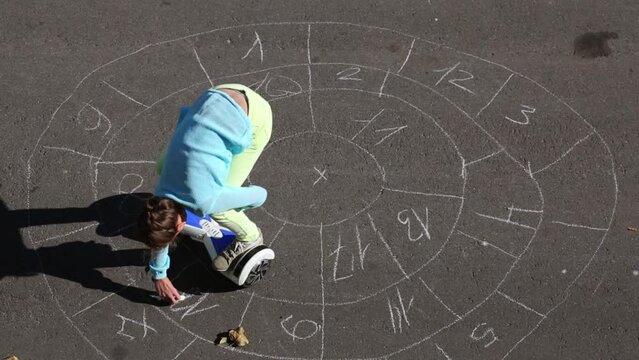 Girl on gyroscooter writes numbers in the sectors on the pavement