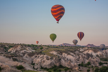 Hot air balloons flying over bizarre rock landscape in Cappadocia. Balloons fly early in the morning. Beautiful hot air balloons in the morning sky. Goreme. Turkey