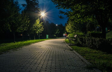 The tiled road in the night park with lanterns in early autumn.