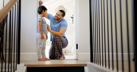 Happy, measuring height and a father with a child writing growth progress on a home wall. Laughing, pride and a dad drawing results of a kid measurement in a house to check for growing together - Powered by Adobe