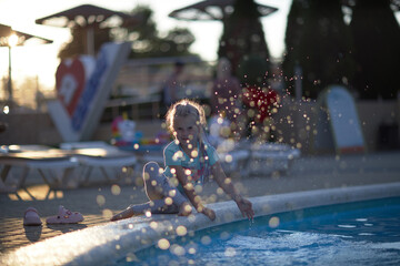 A child, a blonde girl of 6 years old, splashes in the water, sea foam, splashes