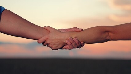 Handshake agreed. Handshake of two businessmen colleagues against background of sun, silhouette of...