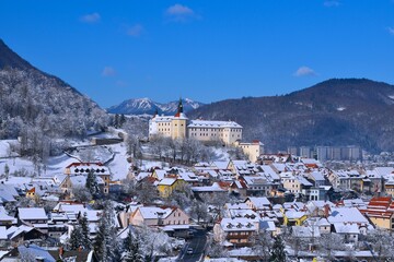 View of Škofja Loka castle and the town bellow in Gorenjska, Slovenia in winter and forest covered hills in the background