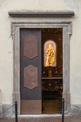 A golden sculpture of virgin Mary and Jesus in a little church, seen through the church door