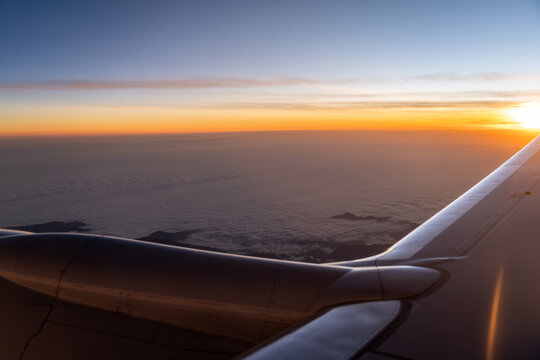 Looking at peascefull sunset from commertial airplane with mountains peaking through the clouds