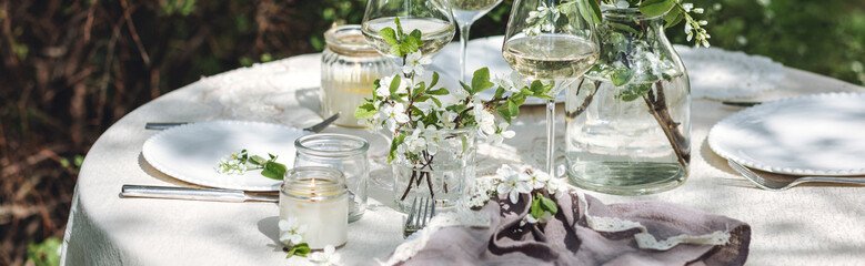 Romantic elegant luxury wedding table decor with white fresh spring blooming cherry apple tree flowers. Glass, candles, floral decoration for special marriage holiday event. Zero waste, banner - obrazy, fototapety, plakaty