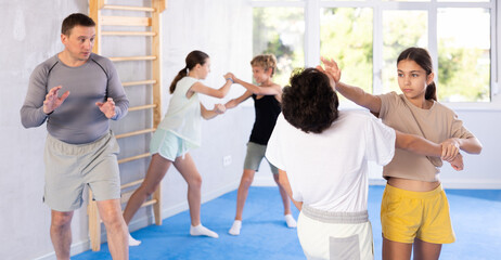 Boy and girl training self-defense techniques in group in studio