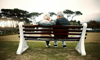 Hug, bench or old couple in park or nature talking or bonding together in retirement outdoors back view. Senior, elderly man or mature woman on date to relax with love, peace or care on calm holiday