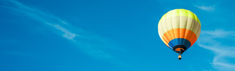 Single hot air balloons flying across the blue sky. Banner, copy space