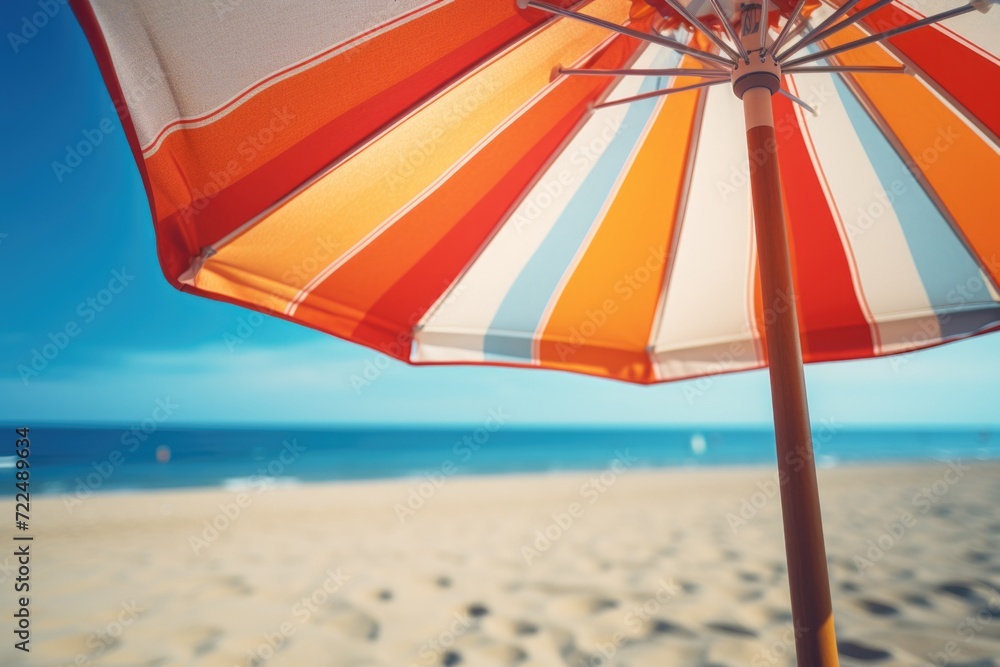 Poster an orange and white striped umbrella on a beach. perfect for adding a pop of color and providing sha
