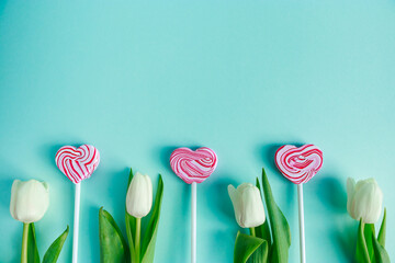 Tulips and lolipop in shape of heart on a blue background. Valentine's day concept, banner format.