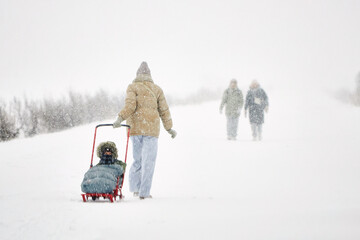Person Pushing Sled With Child in a Winter Snowstorm