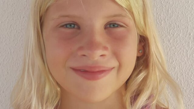 Portrait of blonde smiling girl face near wall close up, smart phone video.