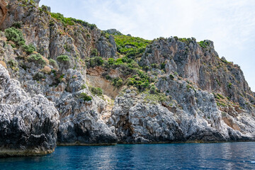 Fototapeta na wymiar Scenic landscape of Island of Corfu, Greece, western shoreline with cliffs and caves at beach and water line of turquoise or deep blue water with breath taking limestone formations