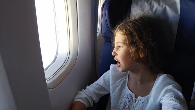Girl yawn and watch in illuminator in flying airplane close up